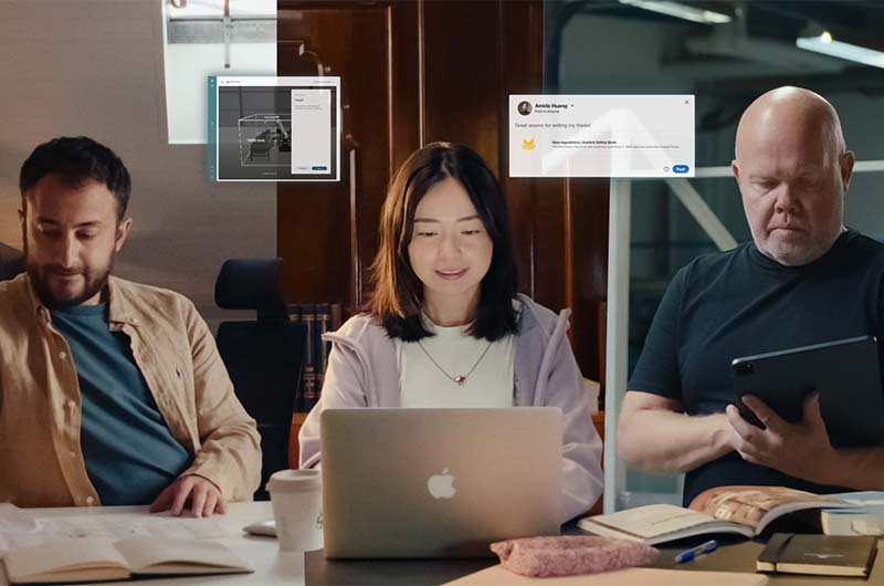 Three people working with laptops, books, and tablets, with digital interface graphics shown above them