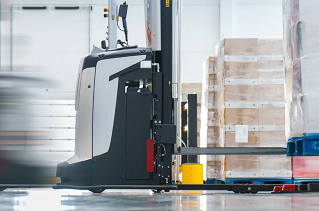 En AGV transporterar en pall i ett lager för automatiserad materialhantering