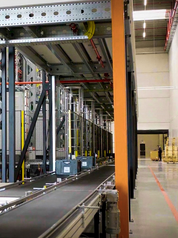 Arbetare som korsar nära ett transportörssystem i lager med säkerhetsbarriärer på plats