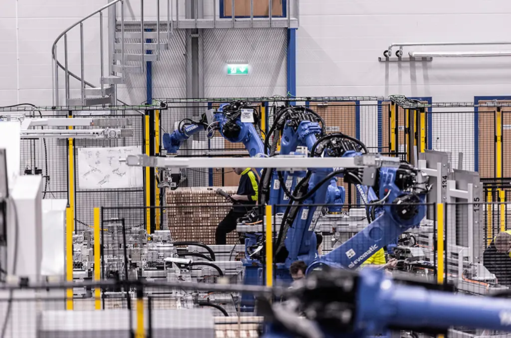 Robotarmer palleterar kartonger inuti en skyddad automatiseringscell