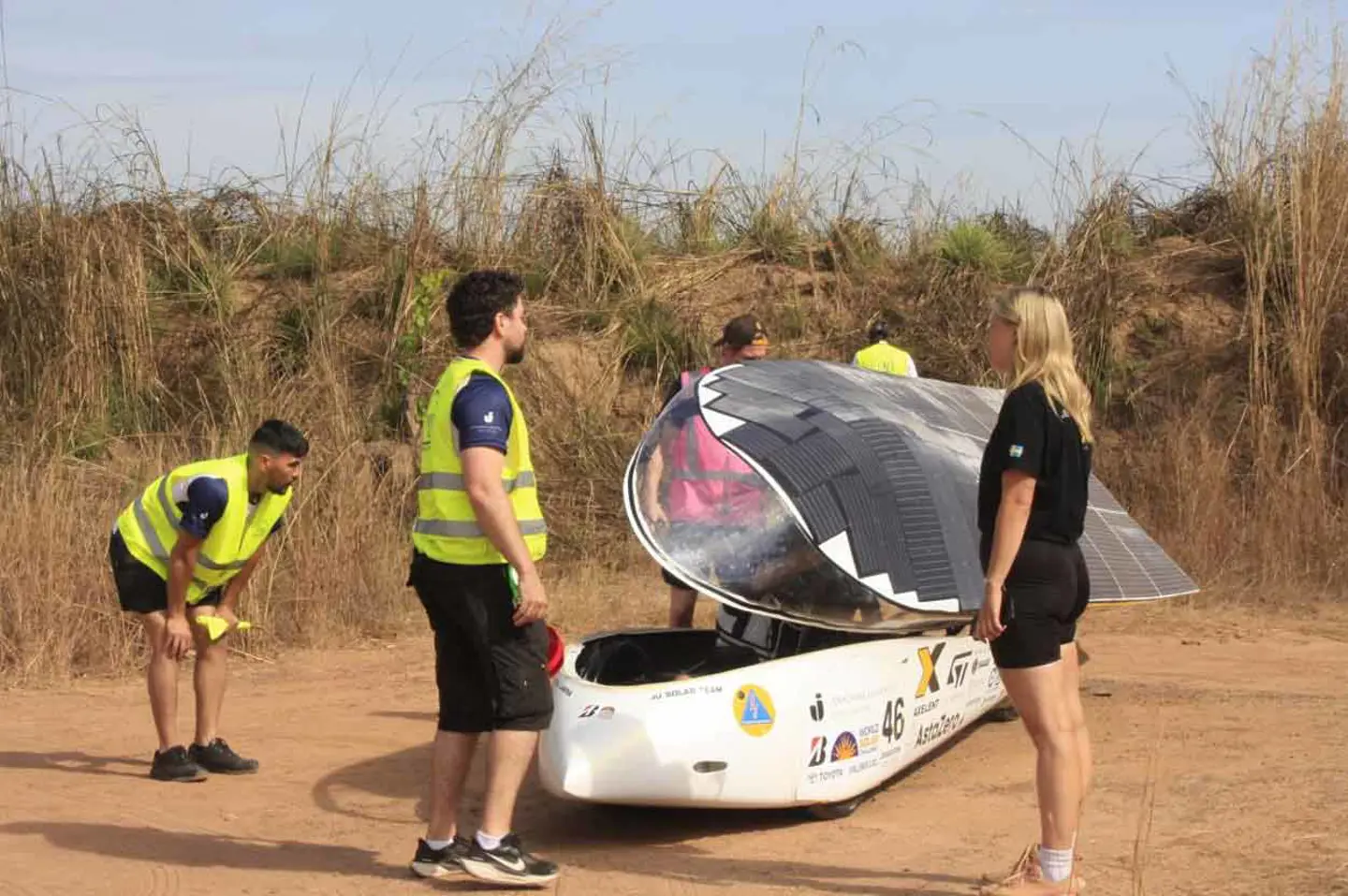 Medlemmar från JU Solar Team '25 står och pratar runt solbilen Nova Lumia.