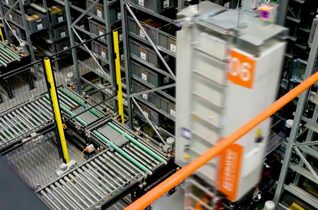 Automatiserat lager med transportband och en snabb rörlig lagringsrobot mellan höga hyllor med lådor.
