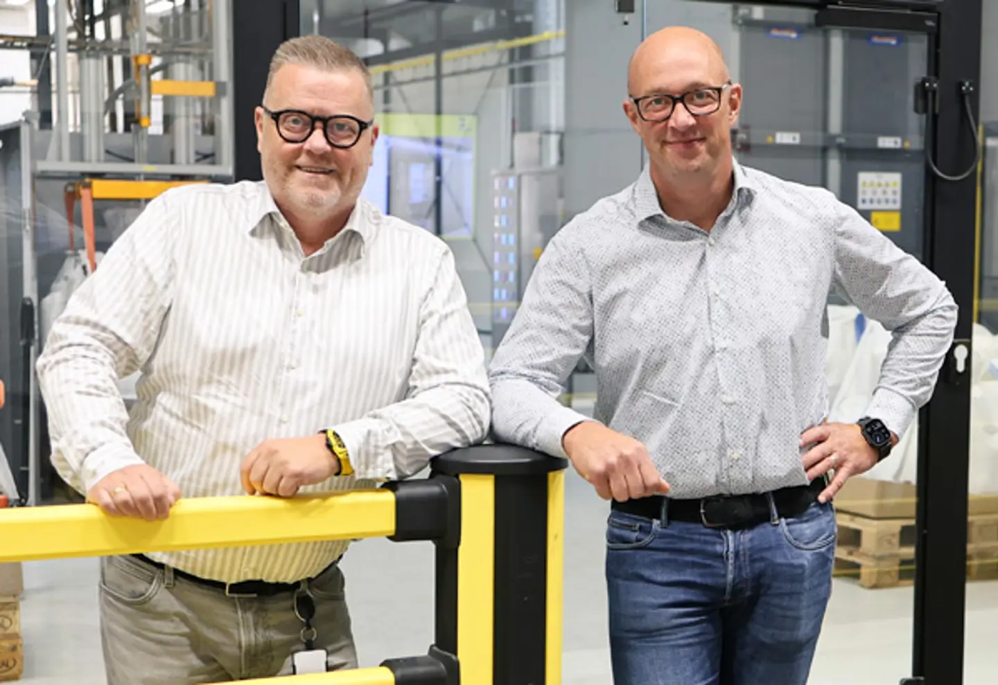 Stefan and Johan Axelsson, ägare av Axelent, står i skjortor avslappnade mot en gul skyddsbarriär