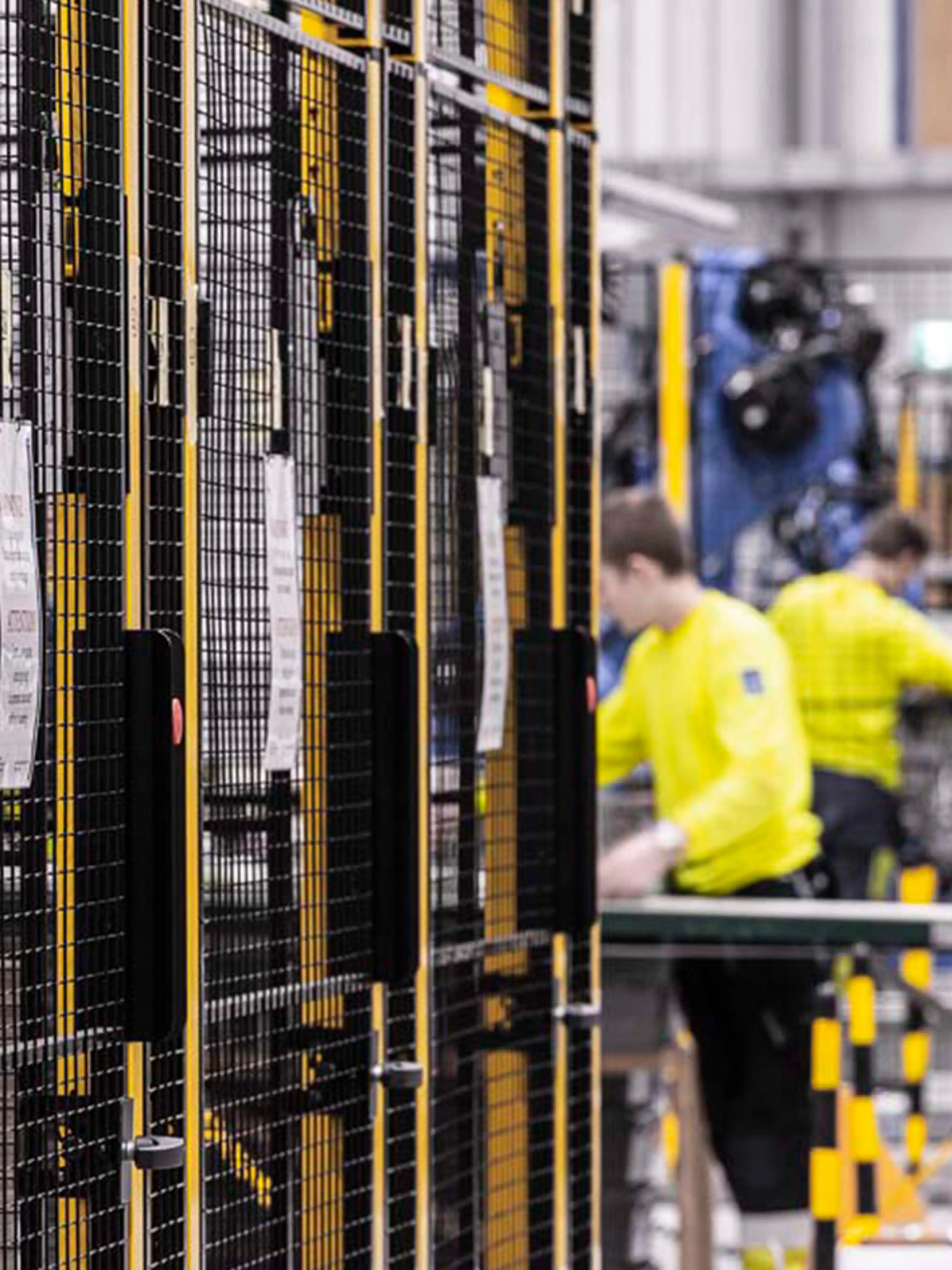 Lager med säkerhetsbarriärer och arbetare nära maskiner, som visar risker där människor och automation samverkar