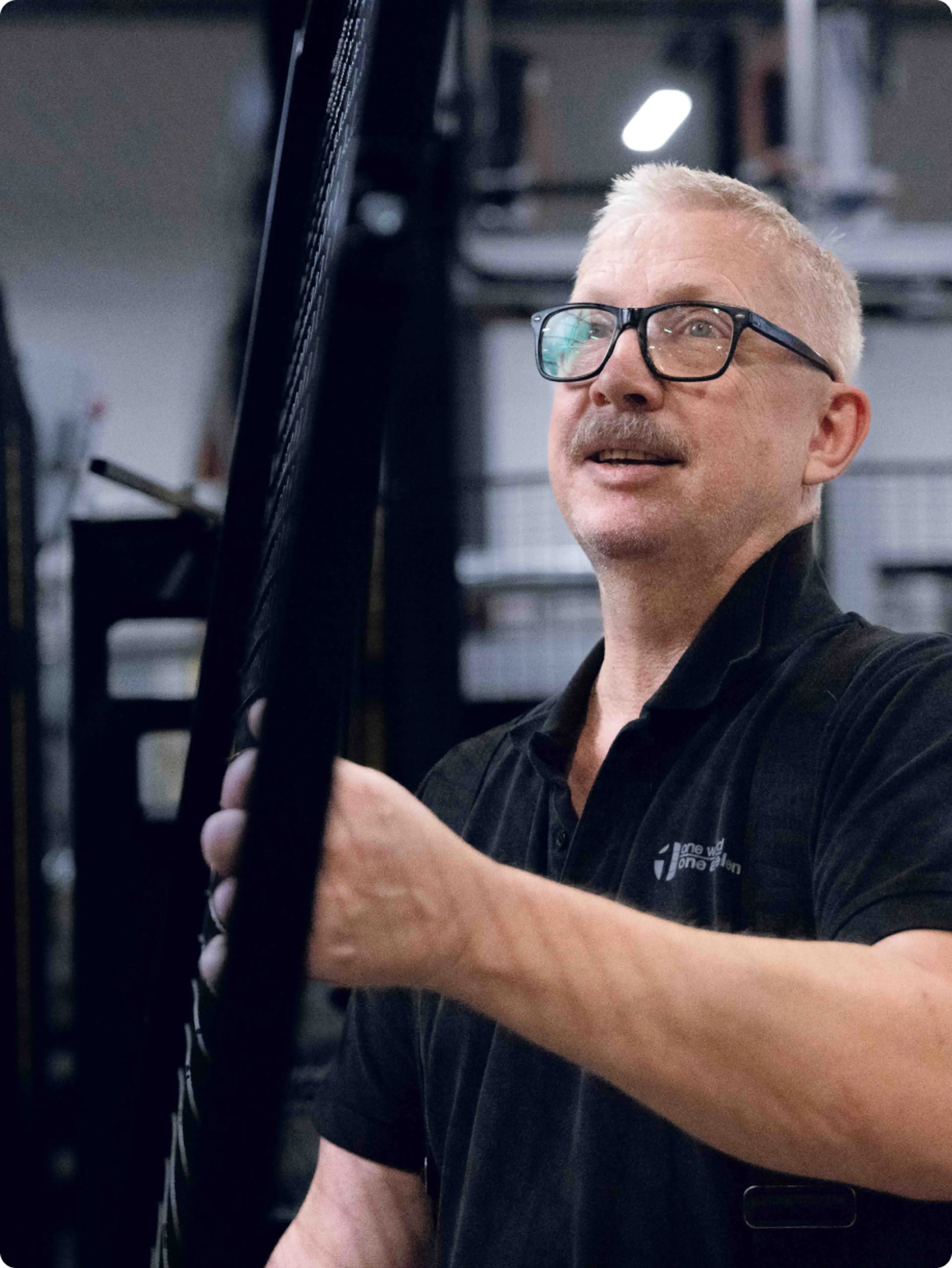 En arbetare inspekterar eller installerar en maskinskyddspanel i en industriell miljö. Bilden visar hur viktigt det är att installera skyddet på rätt sätt och välja rätt säkerhetsbrytare för att säkerställa säker maskindrift och arbetarskydd.