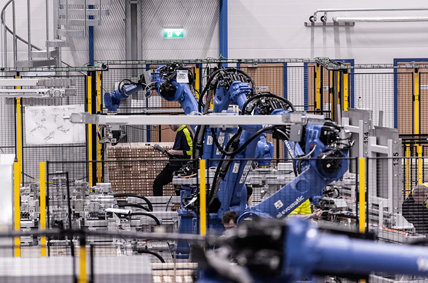 Industriella robotarmar palleterar varor inuti en skyddad automationscell