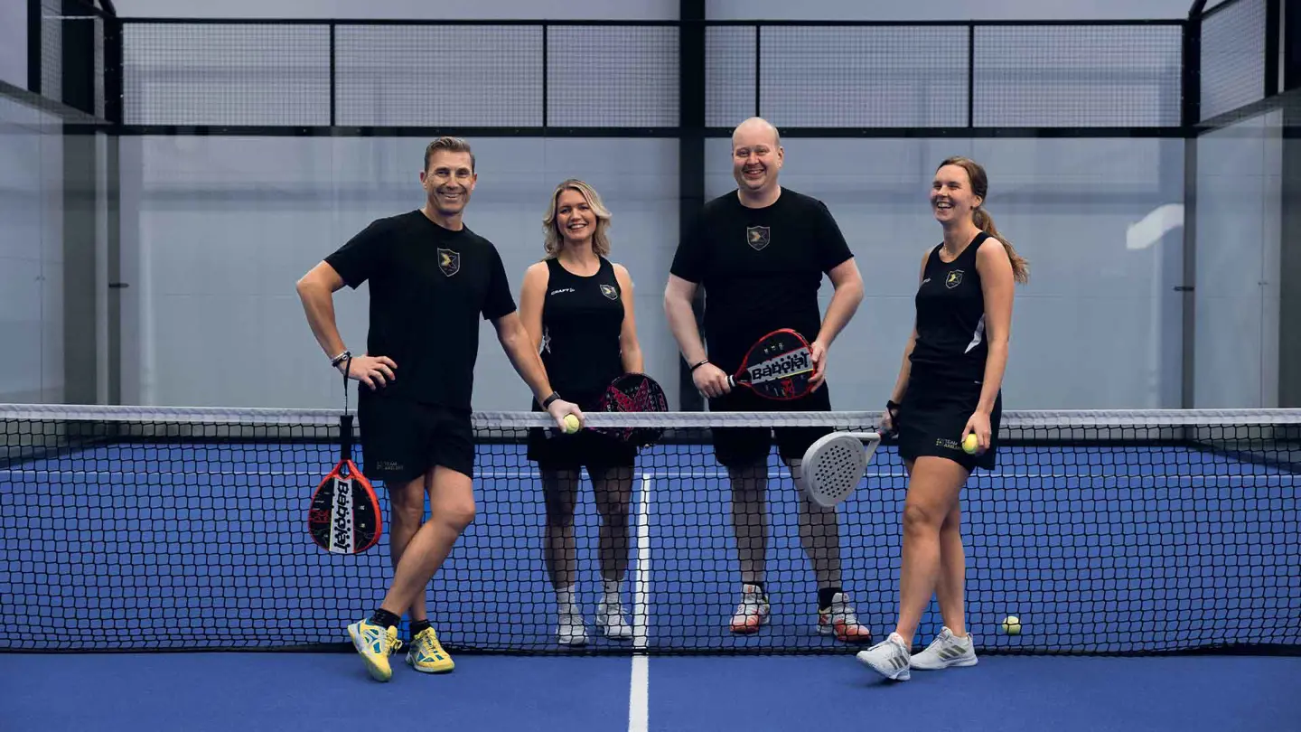 Blå bana i Axelents padelcenter med fyra personer som står tillsammans