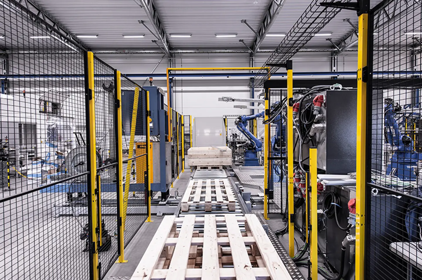 Robotarmer palleterar kartonger inuti en skyddad automatiseringscell