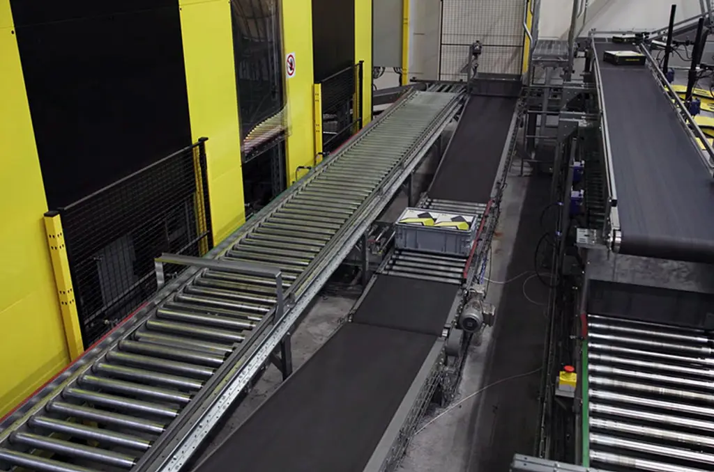 Automatiserat lager med sorteringssystem, transportörer och säkerhetsstängsel för högfartslogistik